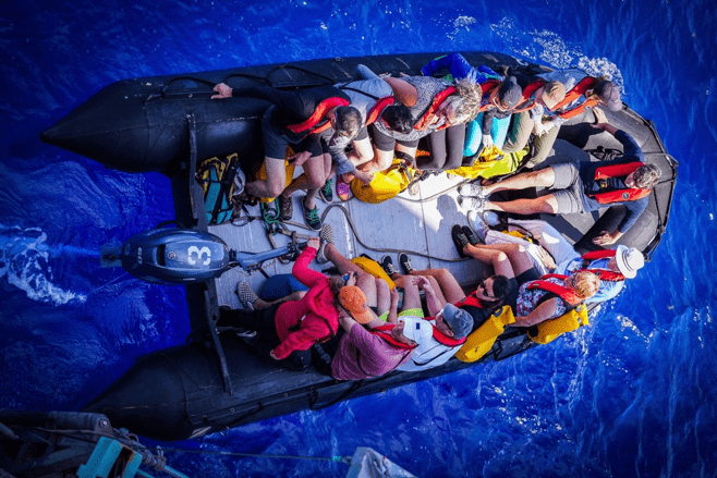 Expedition members in an inflatable boat heading out across open water.